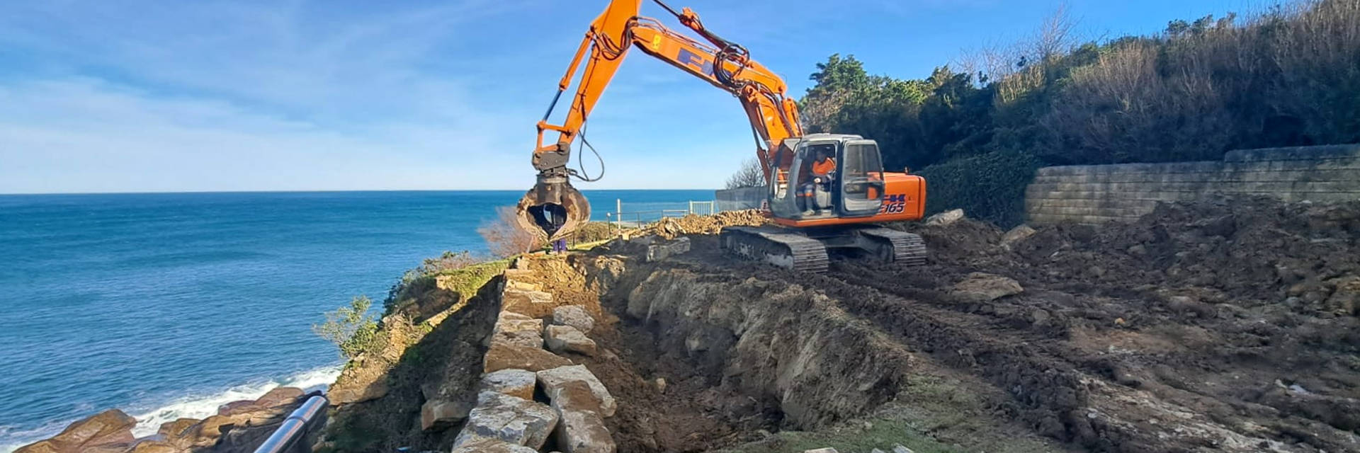 Excavadora haciendo una escollera en la Costa - Excavaciones Bergaretxe